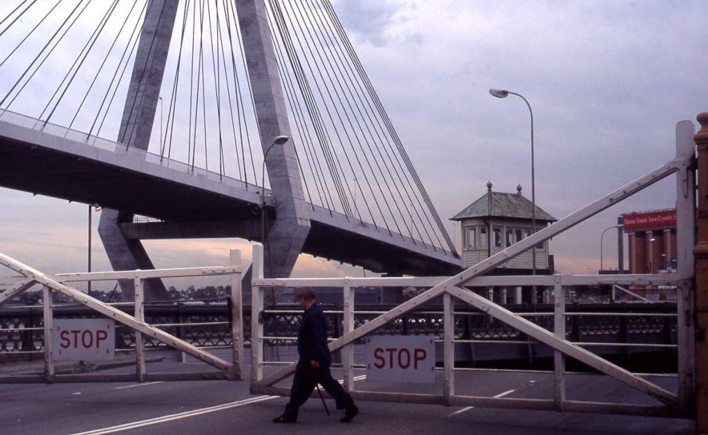 The Control cabin and the closed road traffic gates of the old Glebe Island Bridge with the new Bridge in the background linking Pyrmont with White Bat Rozelle. 1st December 1995. Photographer: John Ward. Image courtesy of City of Sydney Archives